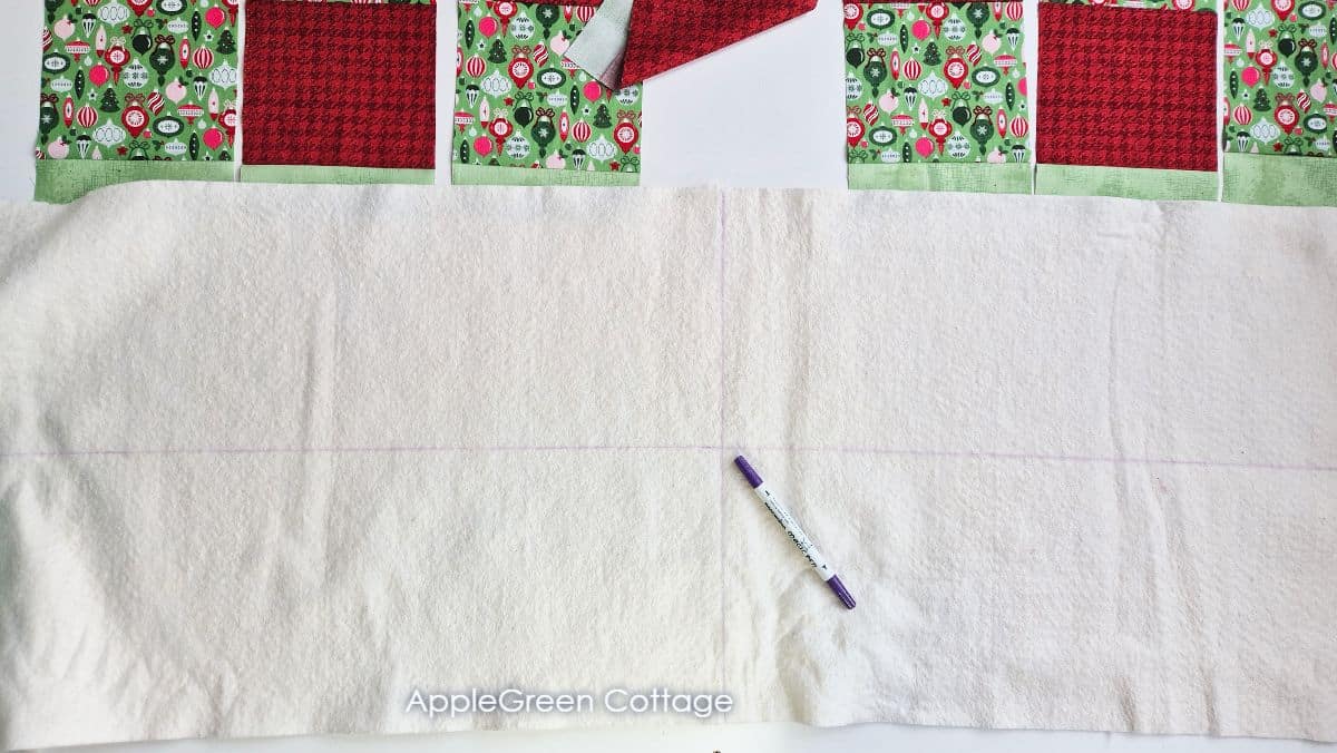 quilt batting with marked center lines, next to quilt blocks ready for piecing