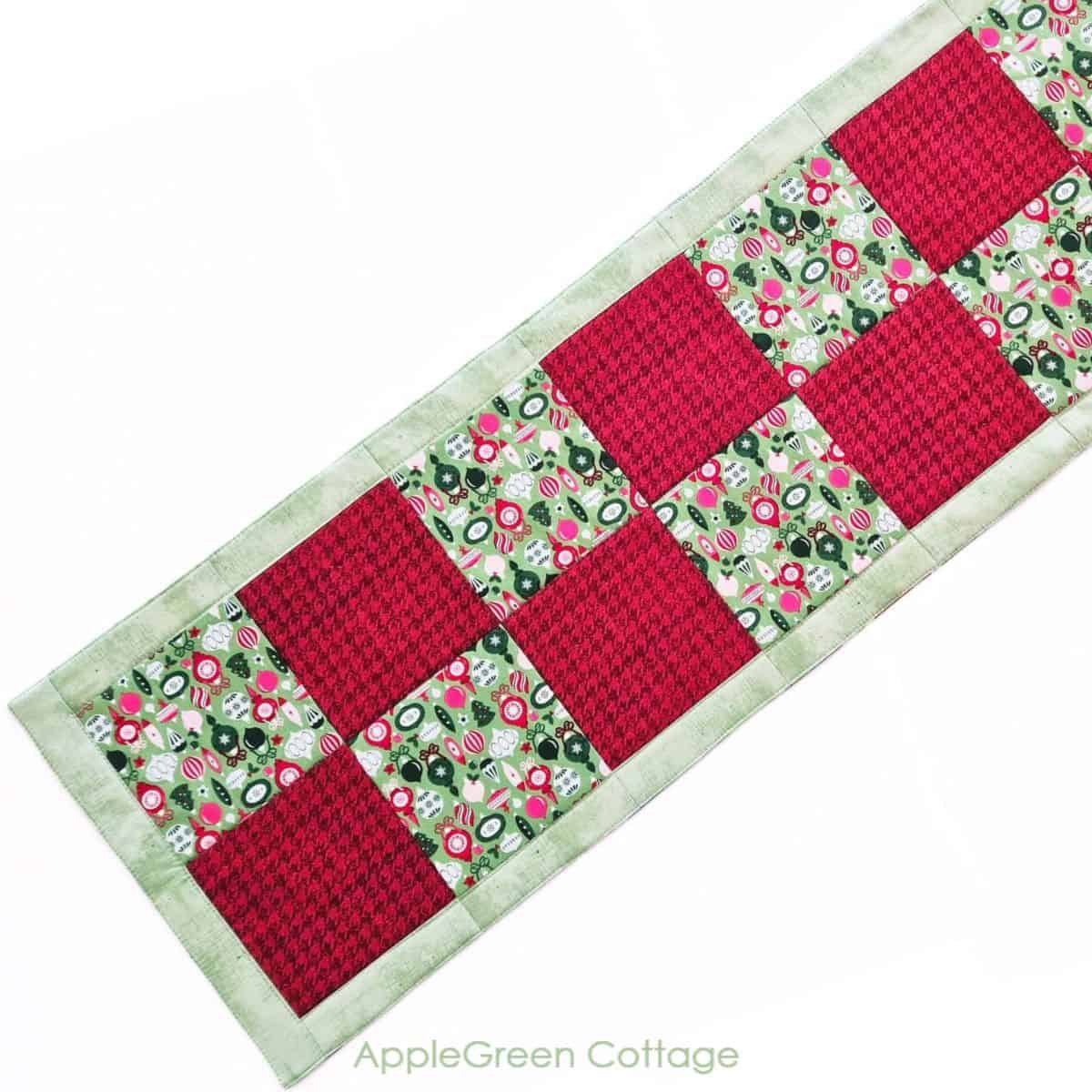 A beautiful quilted Christmas table runner featuring red and green christmas prints, perfect for enhancing holiday dining decor