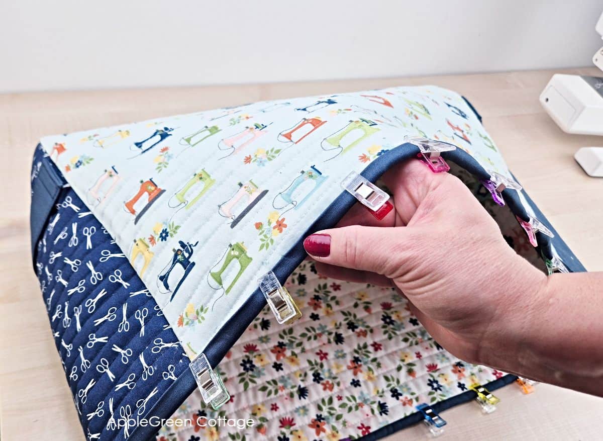 Quilted fabric layers clipped together for the final assembly of a sewing machine cover pattern.