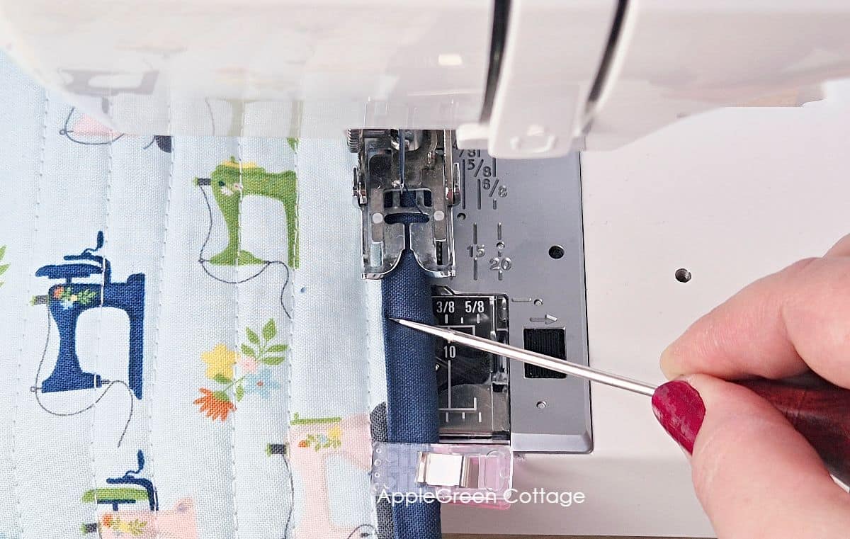 Using a sewing machine to secure straight-grain quilt binding on the edges of a sewing machine cover pattern