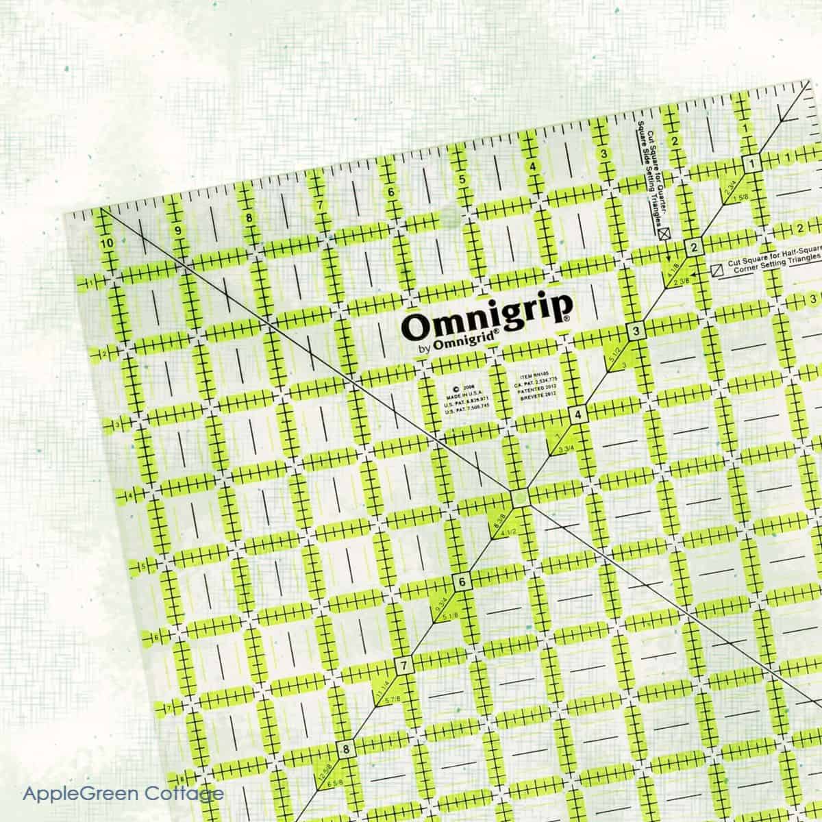 A close-up image of an Omnigrip quilting ruler with bright green and black gridlines, perfect for precise cutting and squaring up quilt blocks. The background features a subtle textured design, adding a clean and modern look.