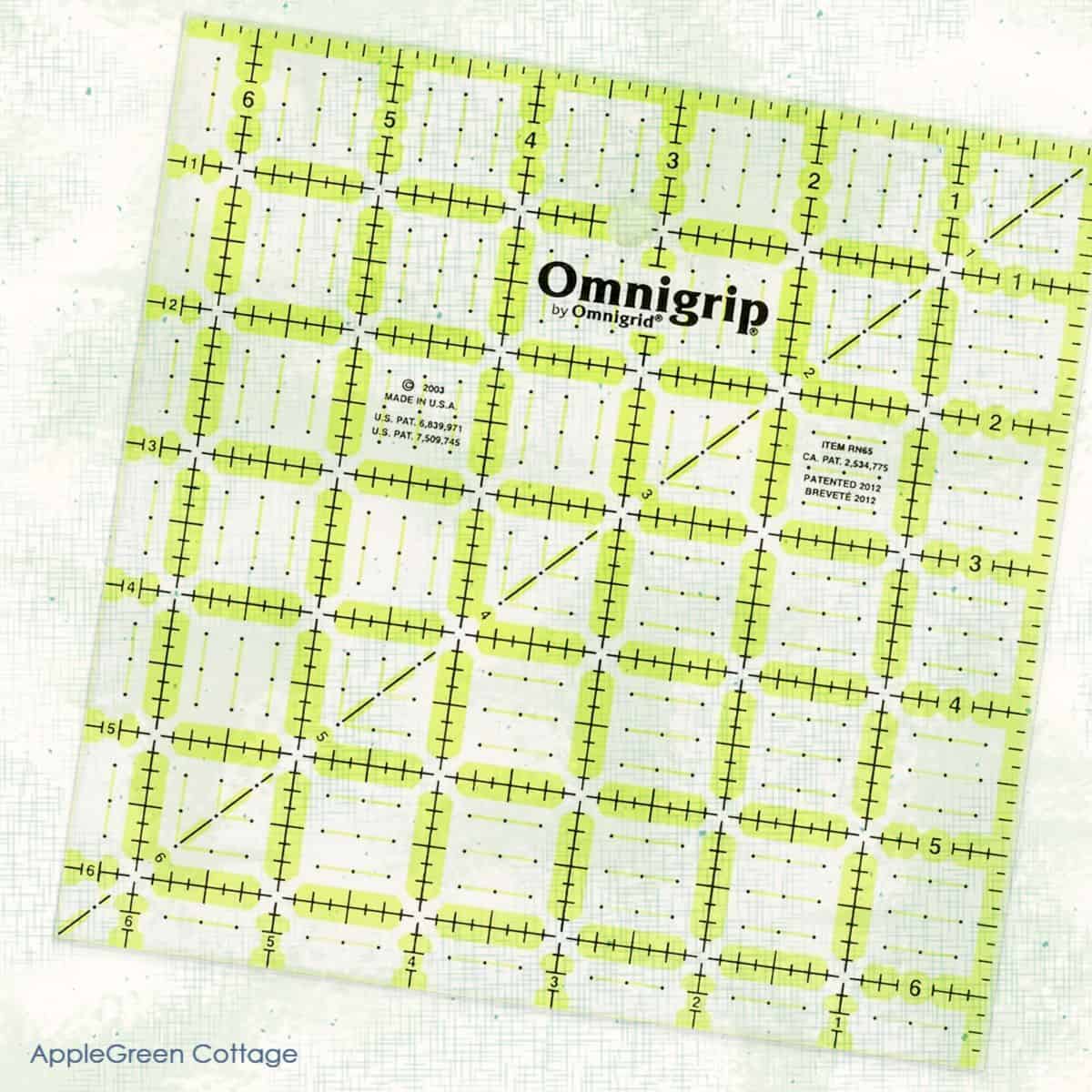 A close-up image of an Omnigrip quilting ruler with bright green and black gridlines, perfect for precise cutting and squaring up quilt blocks. The background features a subtle textured design, adding a clean and modern look.