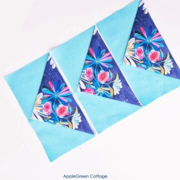 Three vibrant one-seam flying geese blocks arranged in a row, featuring floral and blue fabrics, perfect for quick quilting projects.