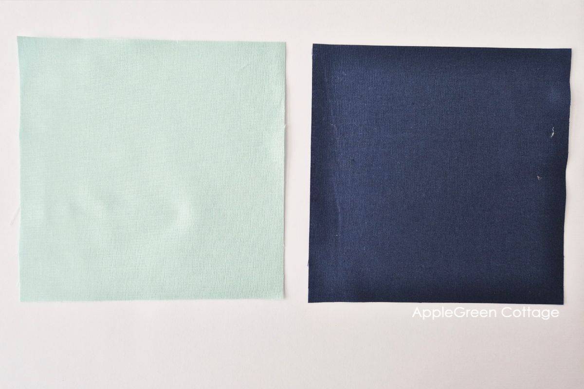 Two fabric squares, one light green and one navy, for Half Square Triangles.