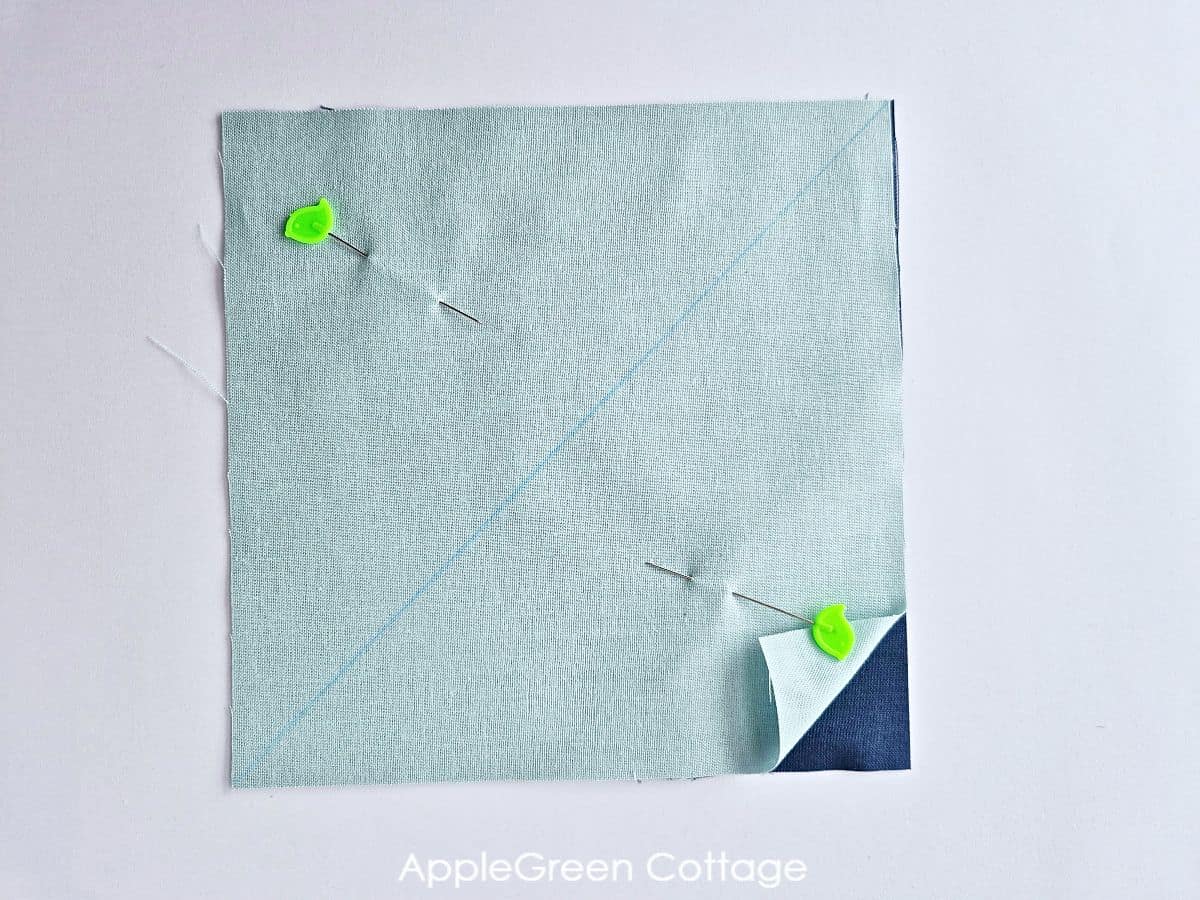 Pinned fabric squares to align for stitching Half Square Triangles.