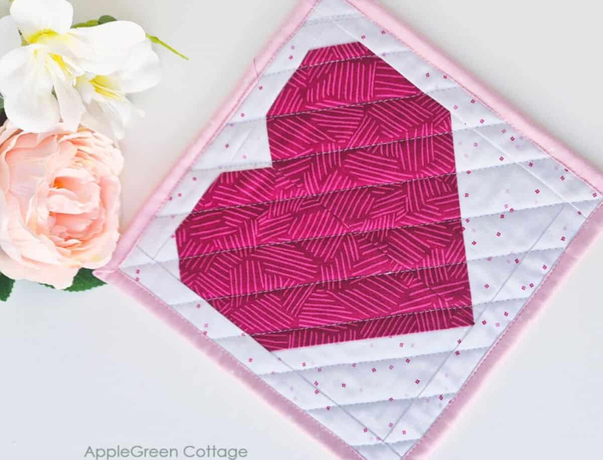 Close-up of a completed pink heart quilt block with floral details, showcasing a beginner-friendly sewing project.