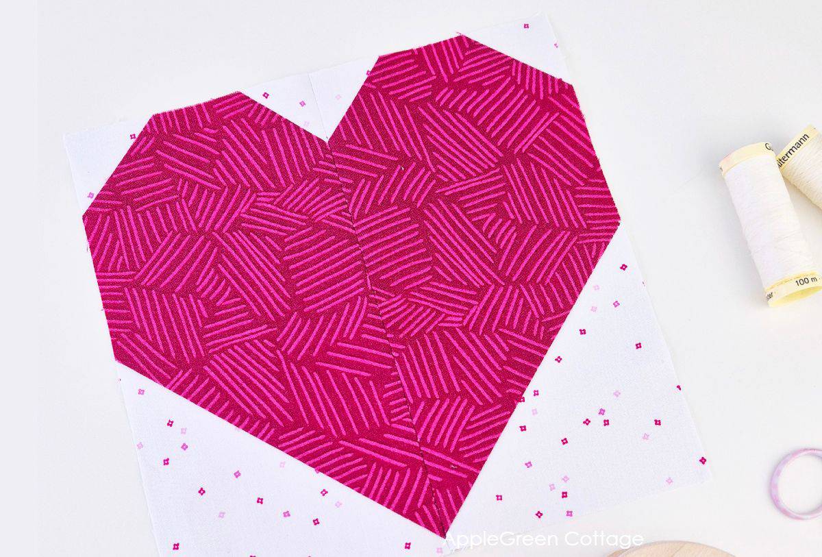 Close-up of a completed pink heart quilt block with intricate patterns, showcasing clean edges and precise sewing for a professional quilting finish.