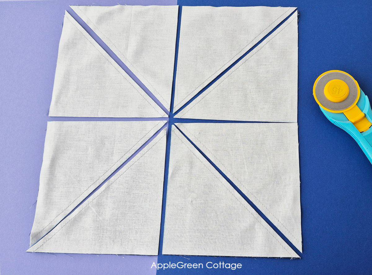 Cutting along the drawn lines to separate the eight HSTs from the fabric square.