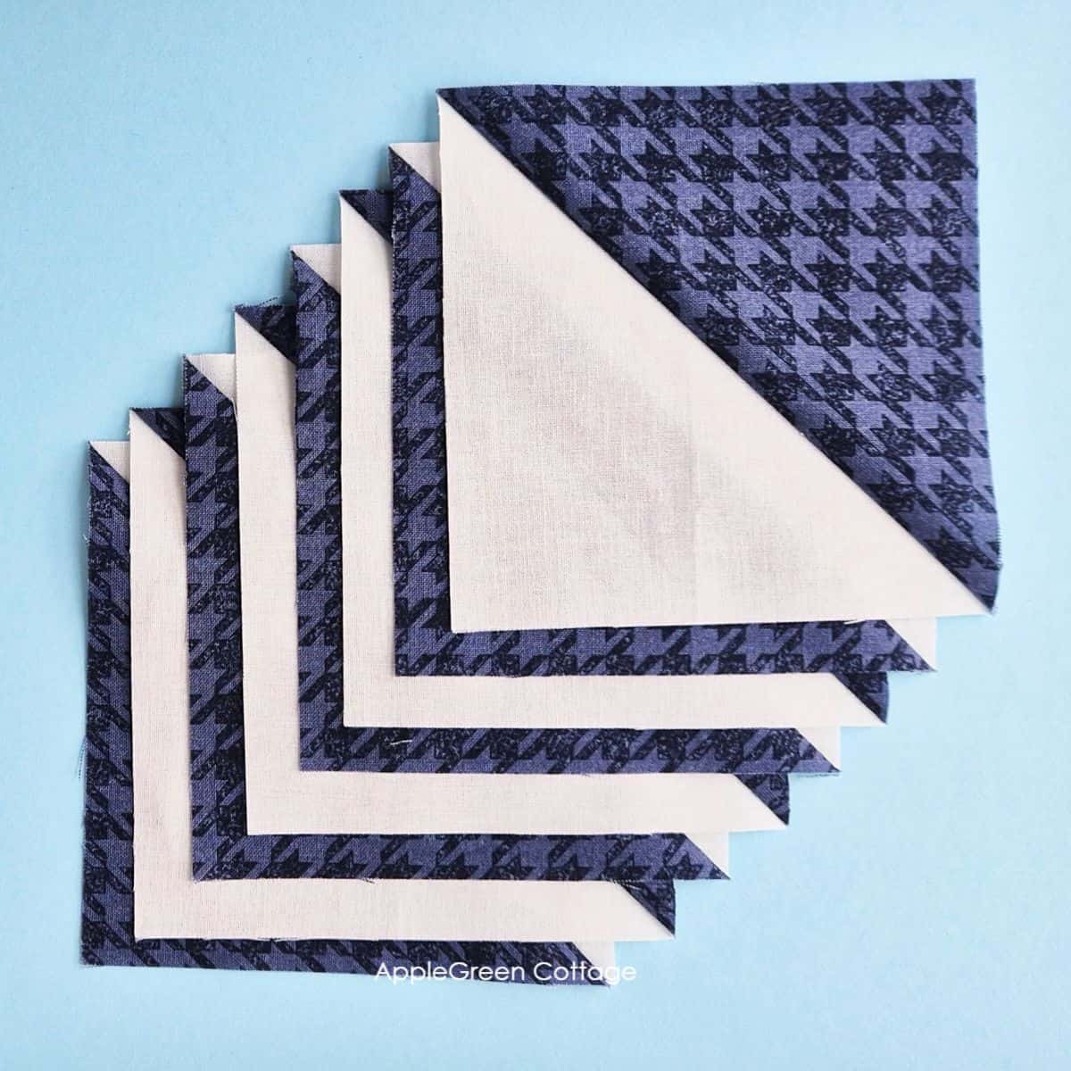 Stack of eight-at-a-time half-square triangles, ready for quilting projects.
