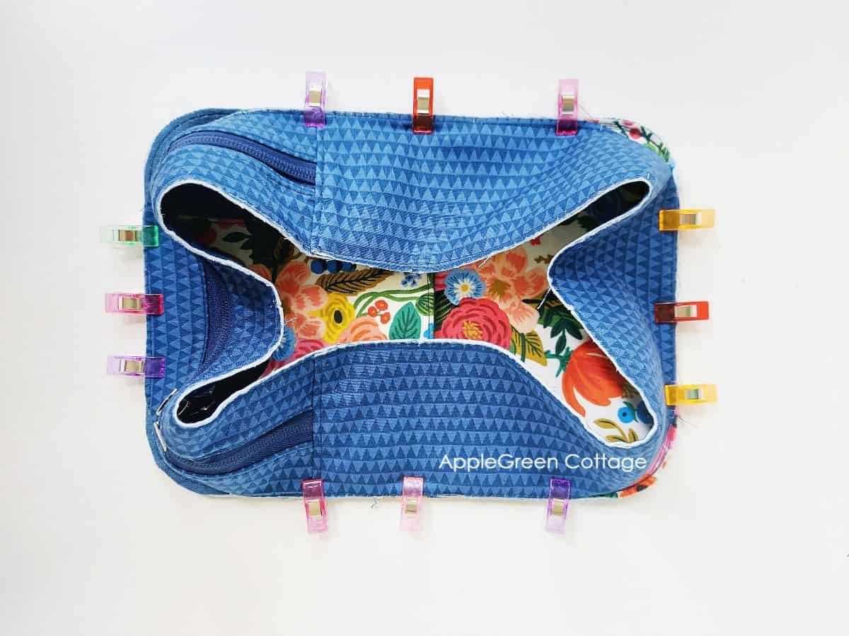 bag gusset in blue fabric with a zipper, attached to the main panel using sewing clips as pin alternatives.