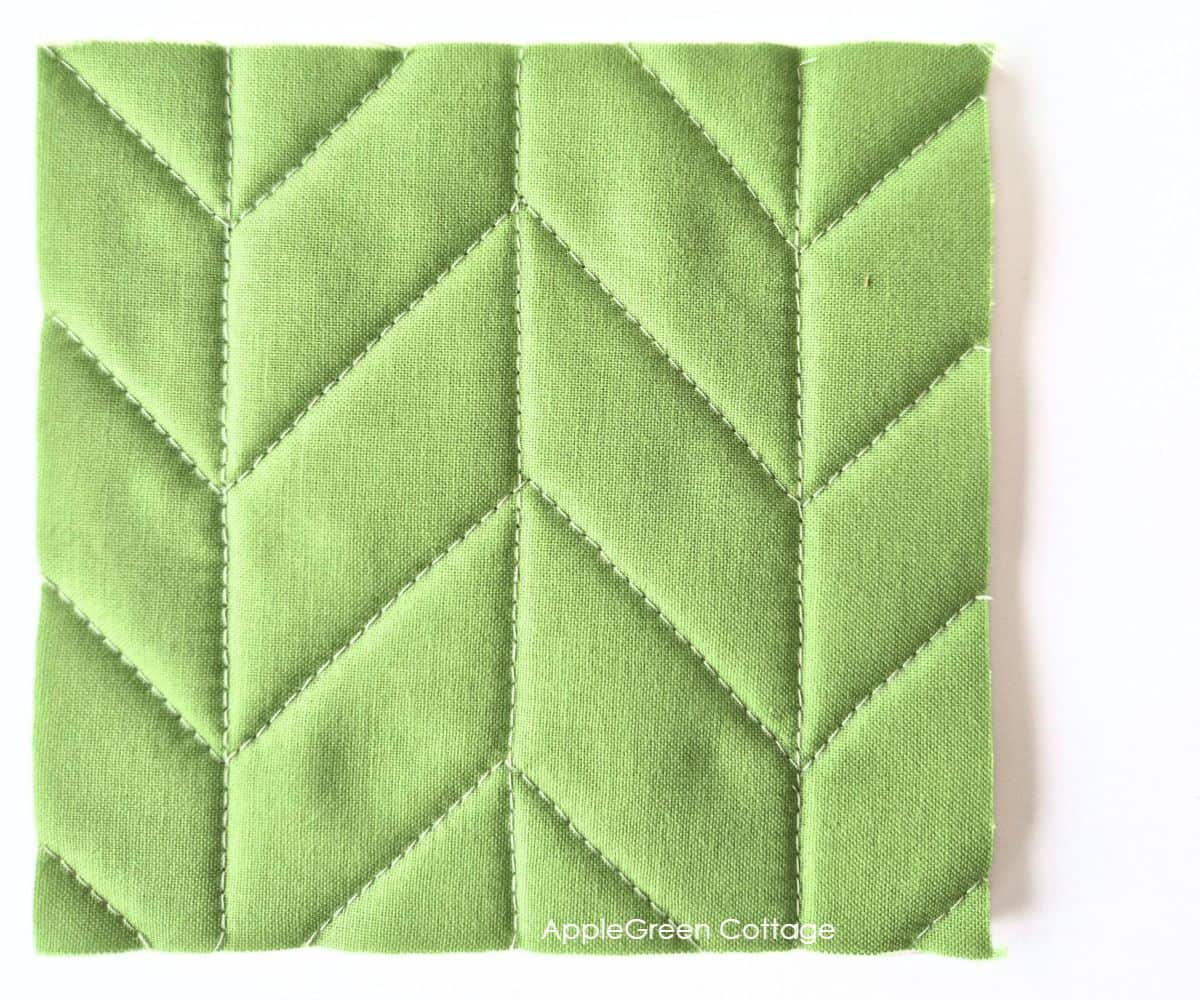 Green quilted fabric with a chevron straight-line quilting pattern.