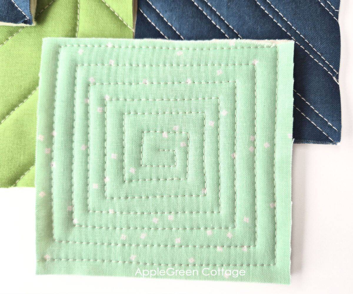 Light green quilted fabric with concentric square quilting stitches.