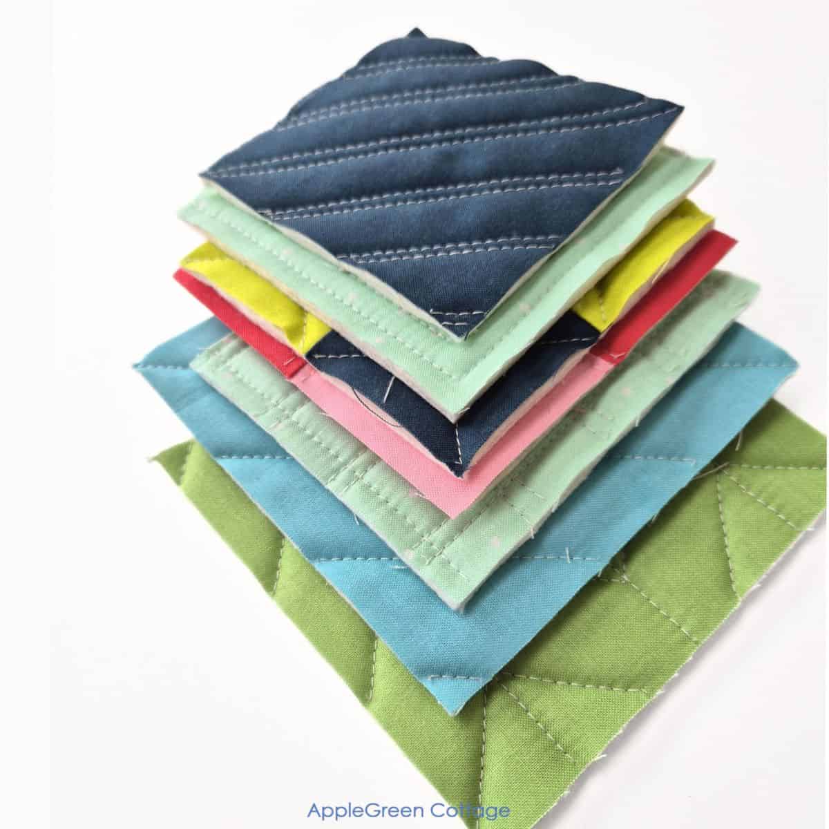 Stack of colorful quilted fabric samples with various straight-line quilting designs.