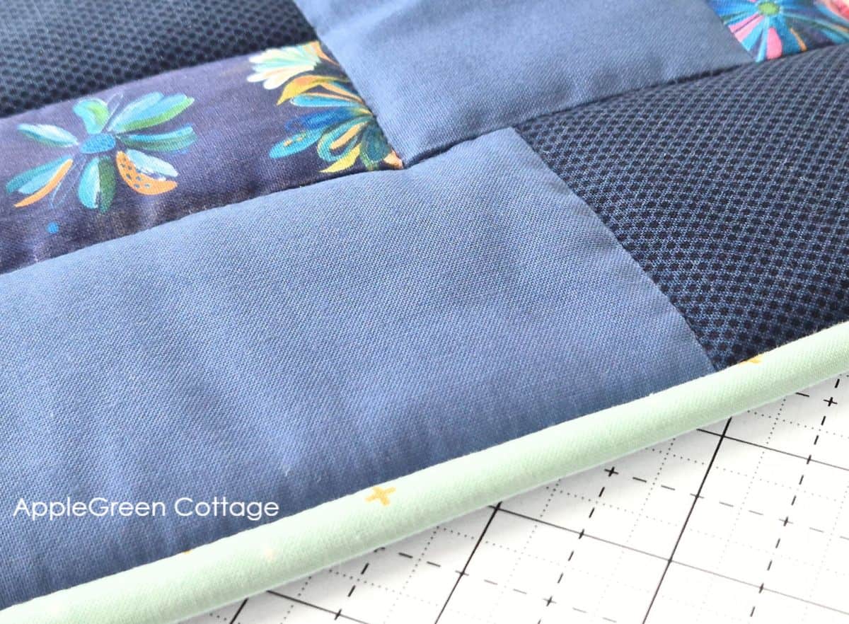 Close-up of a quilted project featuring navy and floral fabric stitched in the ditch, with binding.