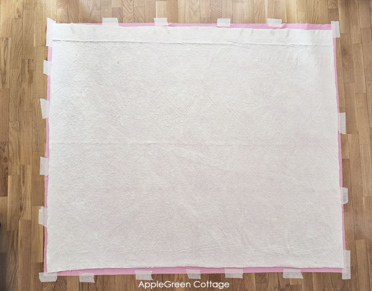 Quilt backing and batting taped to the wooden parquet floor.