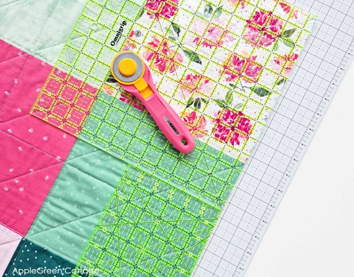 Trimming quilt edges with a rotary cutter and rulers.