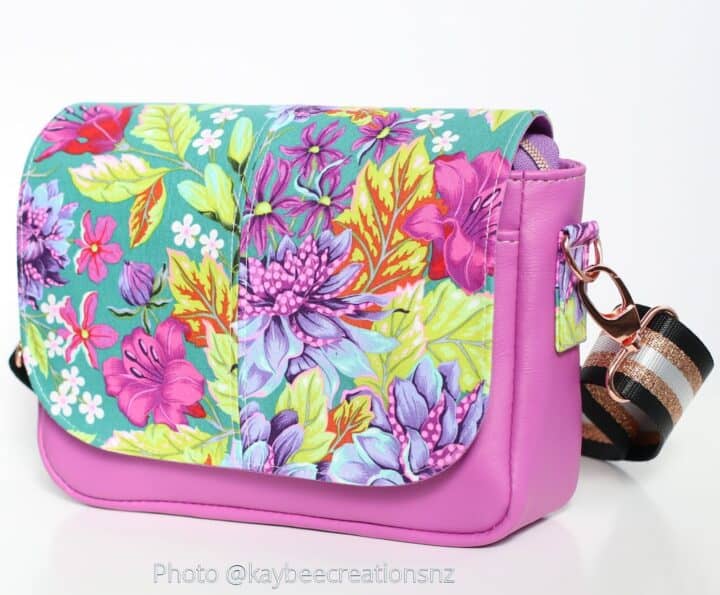 Colorful floral crossbody purse with faux leather bottom and striped strap, perfect for spring outfits.