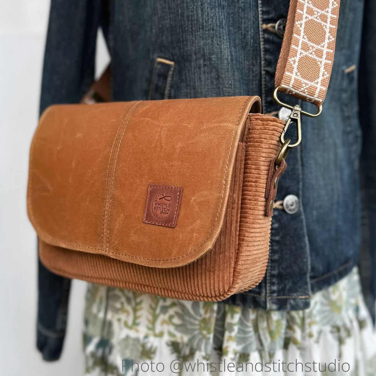 A finished handmade small saddle bag with a flap, sewn with brown corduroy, waxed canvas, and leather