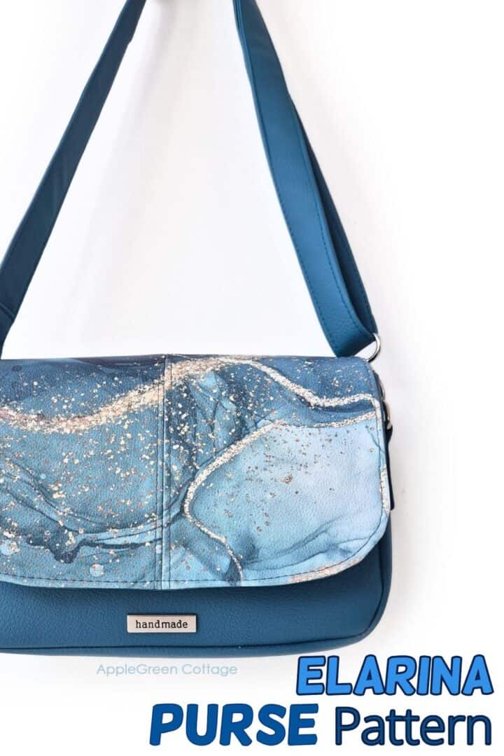 Blue handmade Elarina crossbody bag with marbled flap design, displayed hanging by its strap.