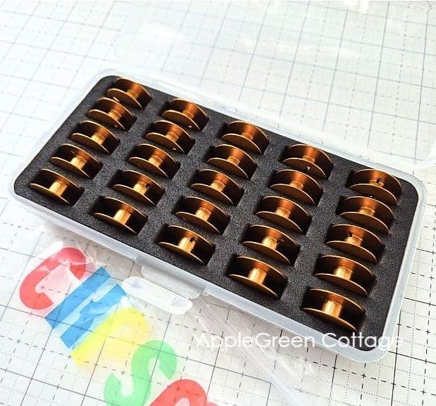 Jumbo bobbins for Janome HD9 version 2 in a case on a sewing table.