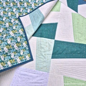 flatlay of a finished modern quilt in white, aqua, green and teal, using an applegreencottage quilt pattern.
