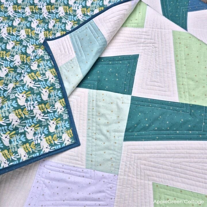 flatlay of a finished modern quilt in white, aqua, green and teal, using an applegreencottage quilt pattern.