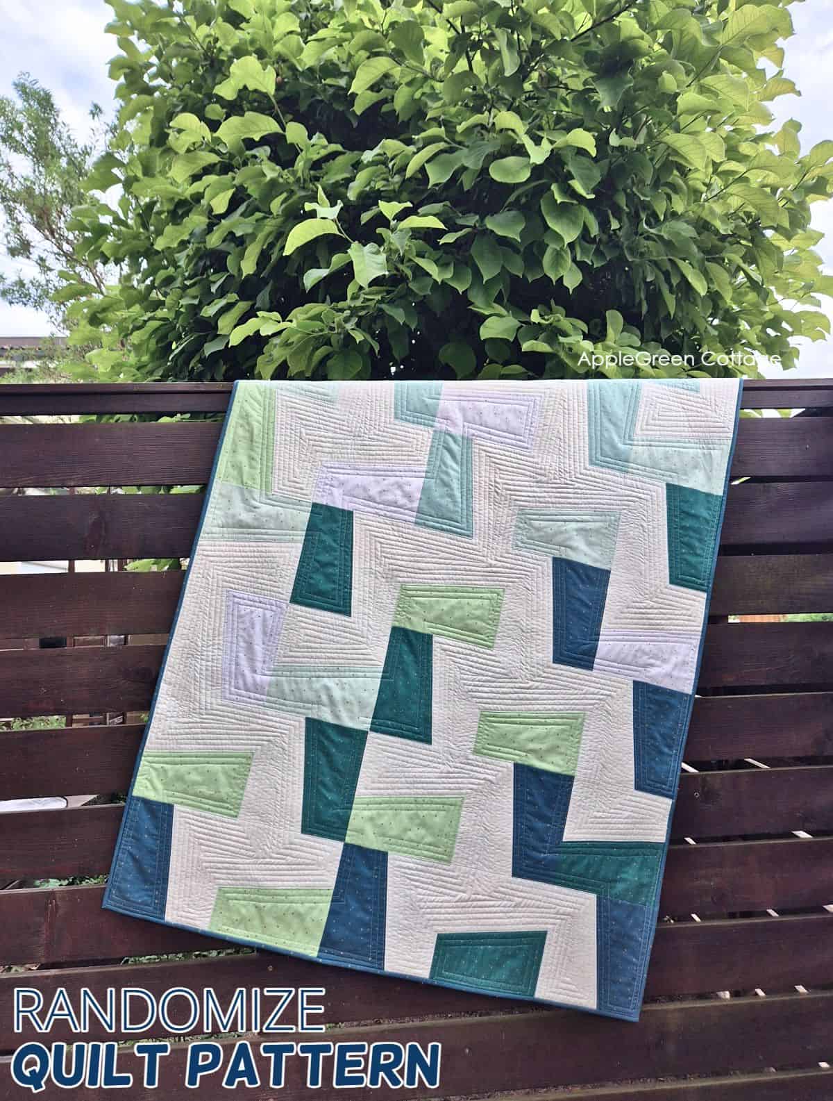 Modern throw quilt with angled blocks in blues and greens hanging outdoors – Randomize Quilt Pattern by AppleGreen Cottage.
