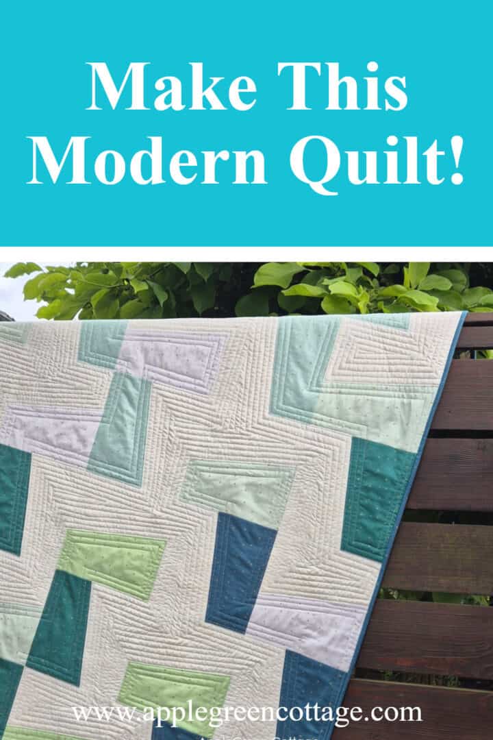 Modern throw quilt with angled blocks in blues and greens hanging outdoors – Randomize Quilt Pattern by AppleGreen Cottage.