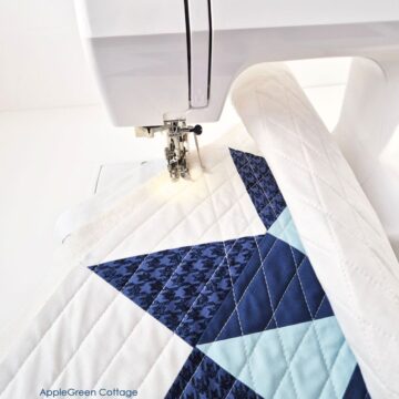 Sewing a blue and white quilt block using a walking foot on a home sewing machine.