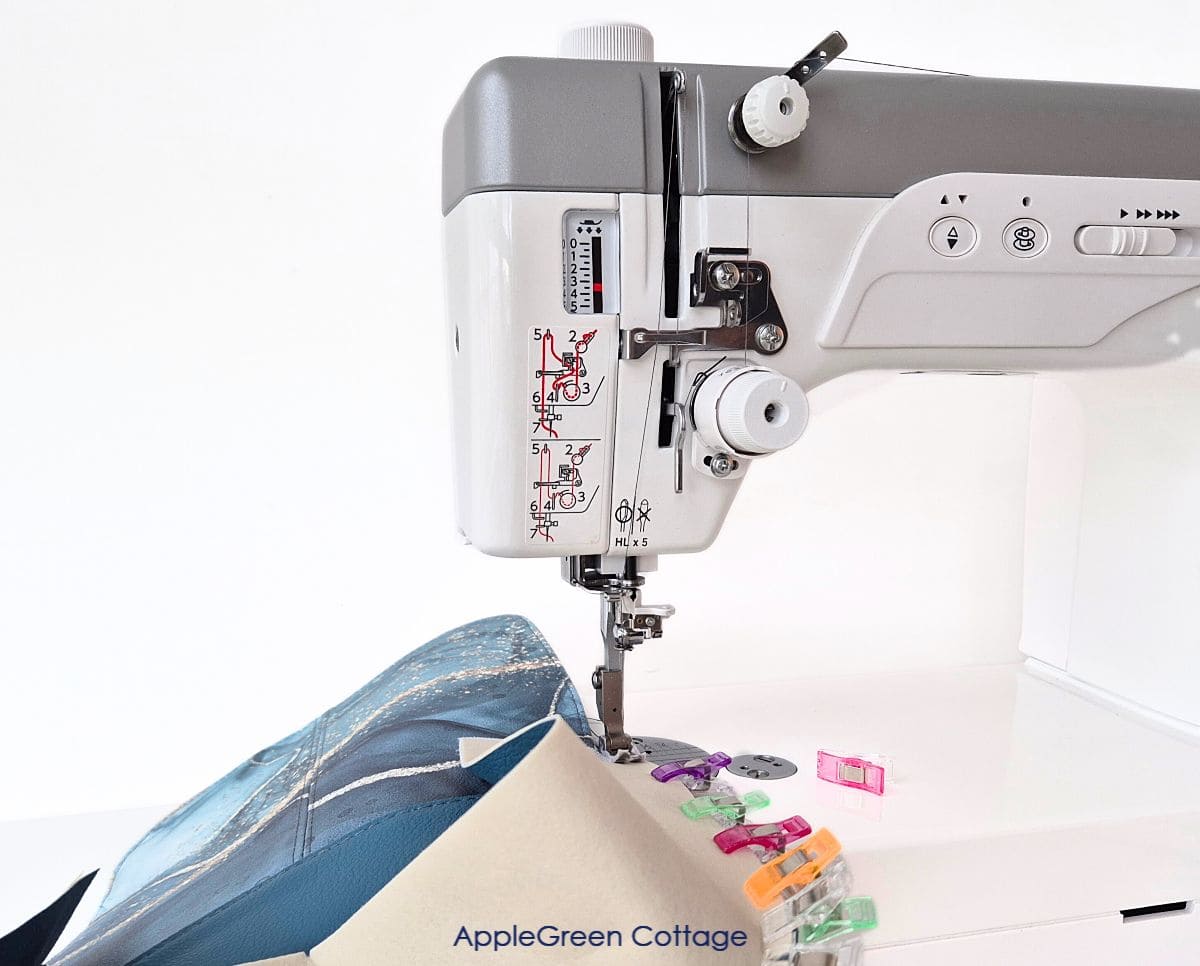 A bag panel with two blue vinyl pieces, a layer of Decovil Light, and a topstitched flap being sewn on the Janome HD9 prfessional machine