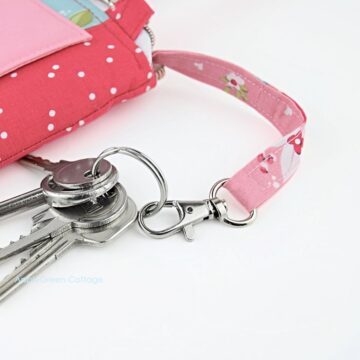 A finished wallet bag with an inserted detachable keyholder in beautiful red floral print with keys attached.