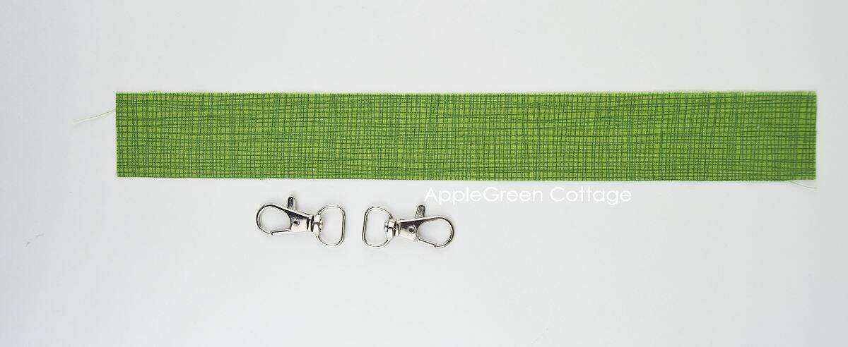 green fabric cut for a keyholder strap and two swivel hooks.