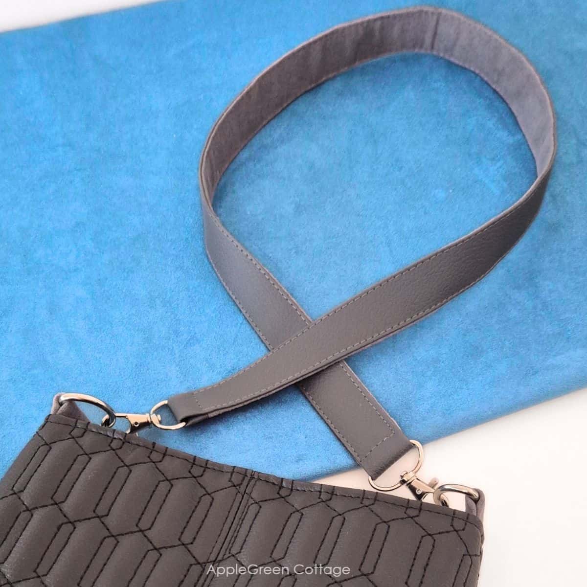 Finished faux leather shoulder strap attached to a faux leather bag.