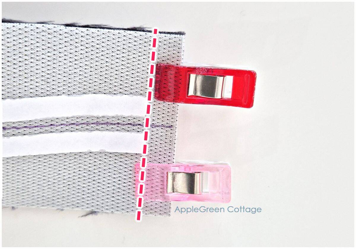 Quilting clips holding strap layers together before sewing with marked seam guide.