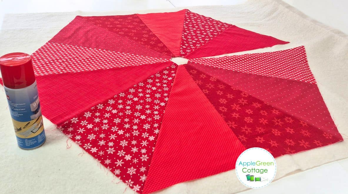 Spray basting red quilted tree skirt top to batting before quilting.