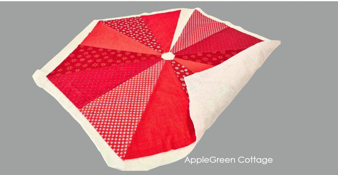 Layered red quilted tree skirt top over batting, ready for trimming and quilting.