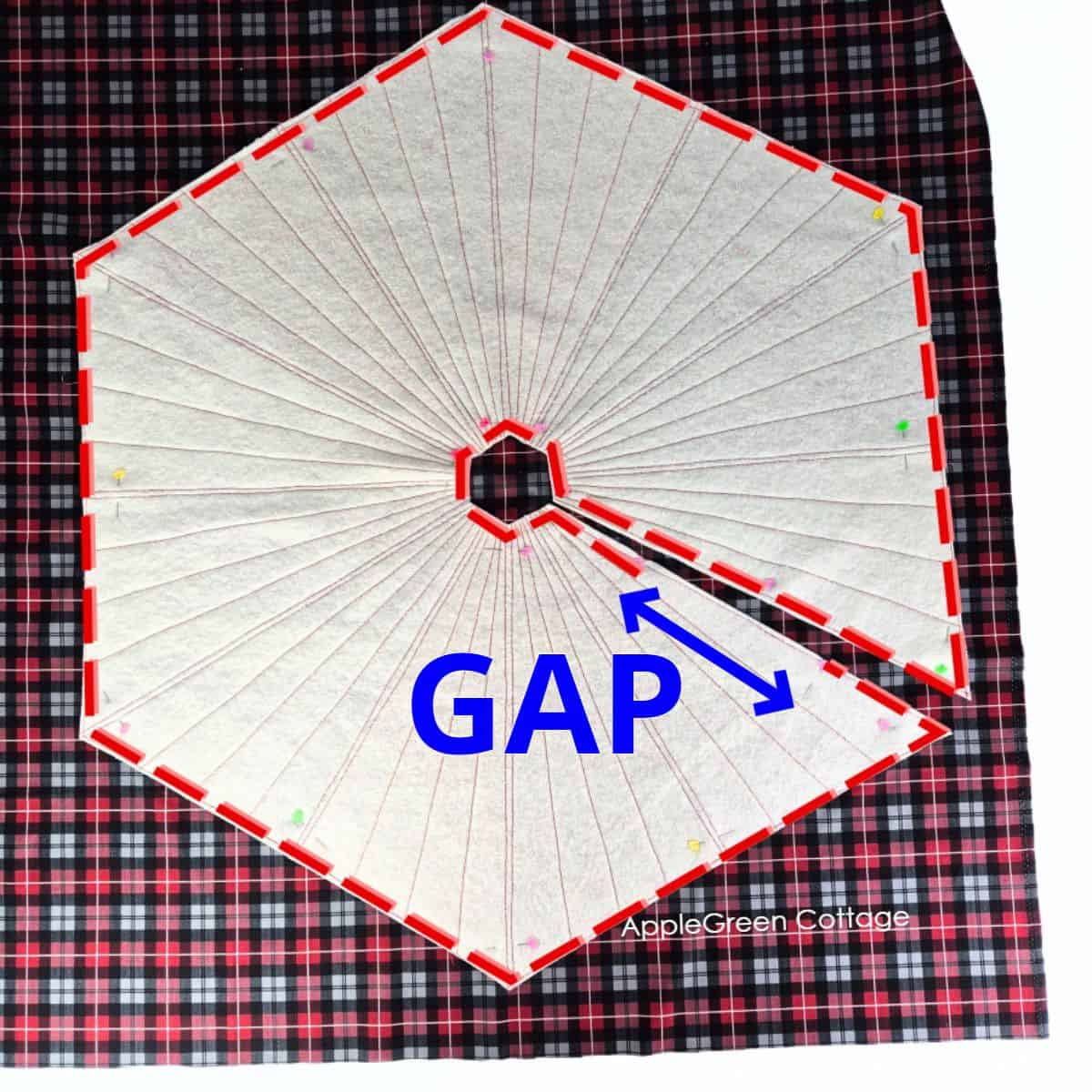Placing quilted red tree skirt top on plaid backing fabric, leaving a center opening gap and pinning around edges for sewing.