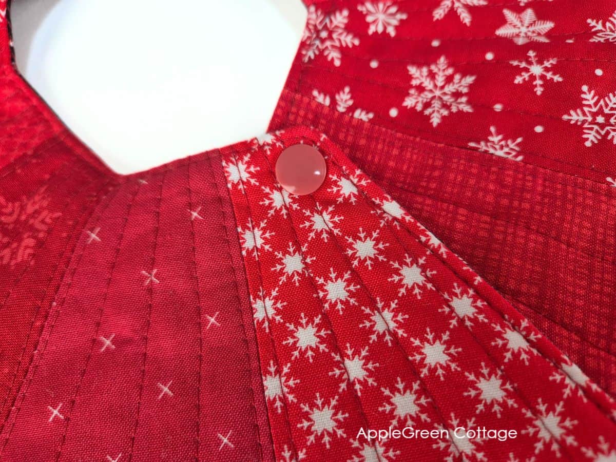 Close-up of red snap fastening on quilted Christmas tree skirt sewing project.