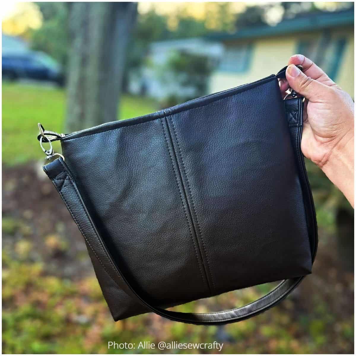 Handmade black faux leather Lumera crossbody bag with center seam and silver hardware.