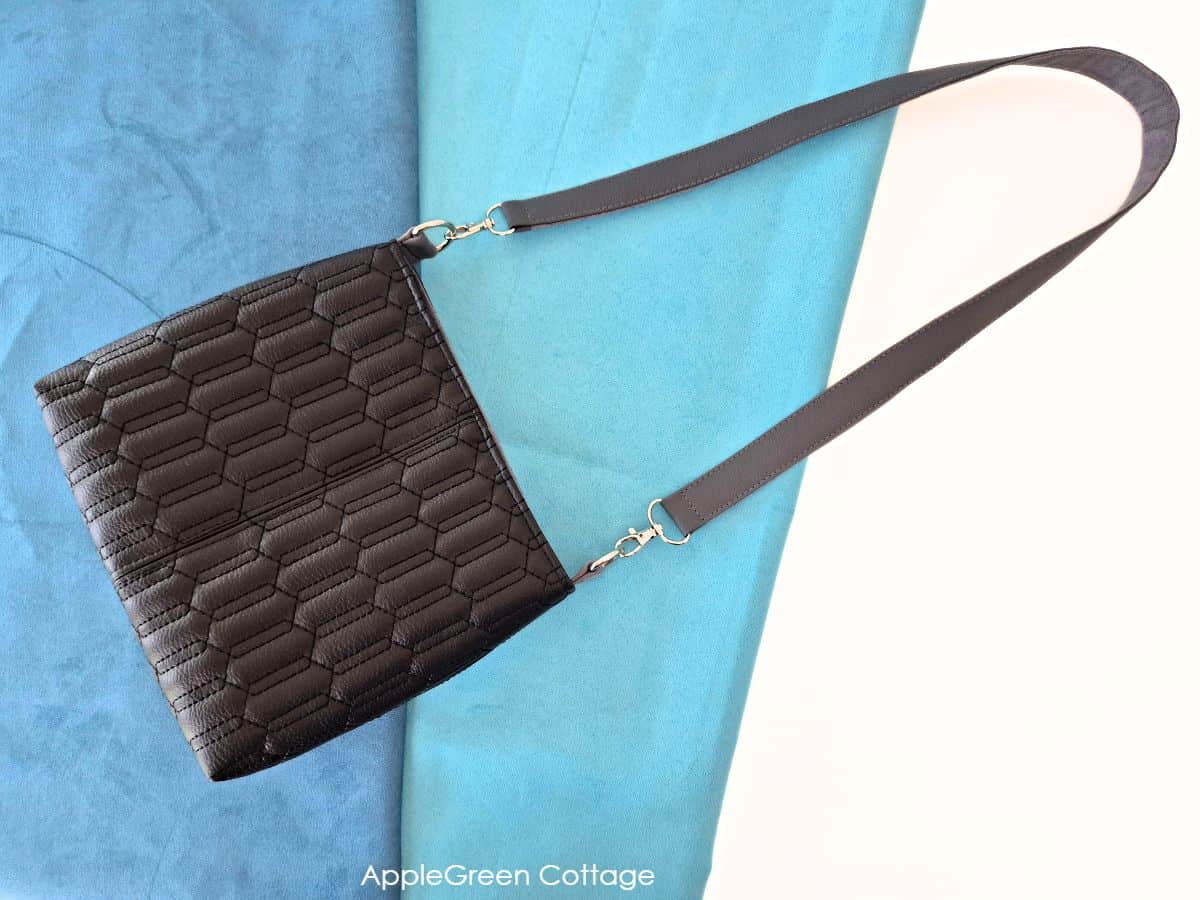 A beautiful handmade black faux leather bag with a sleek faux leather shoulder strap.