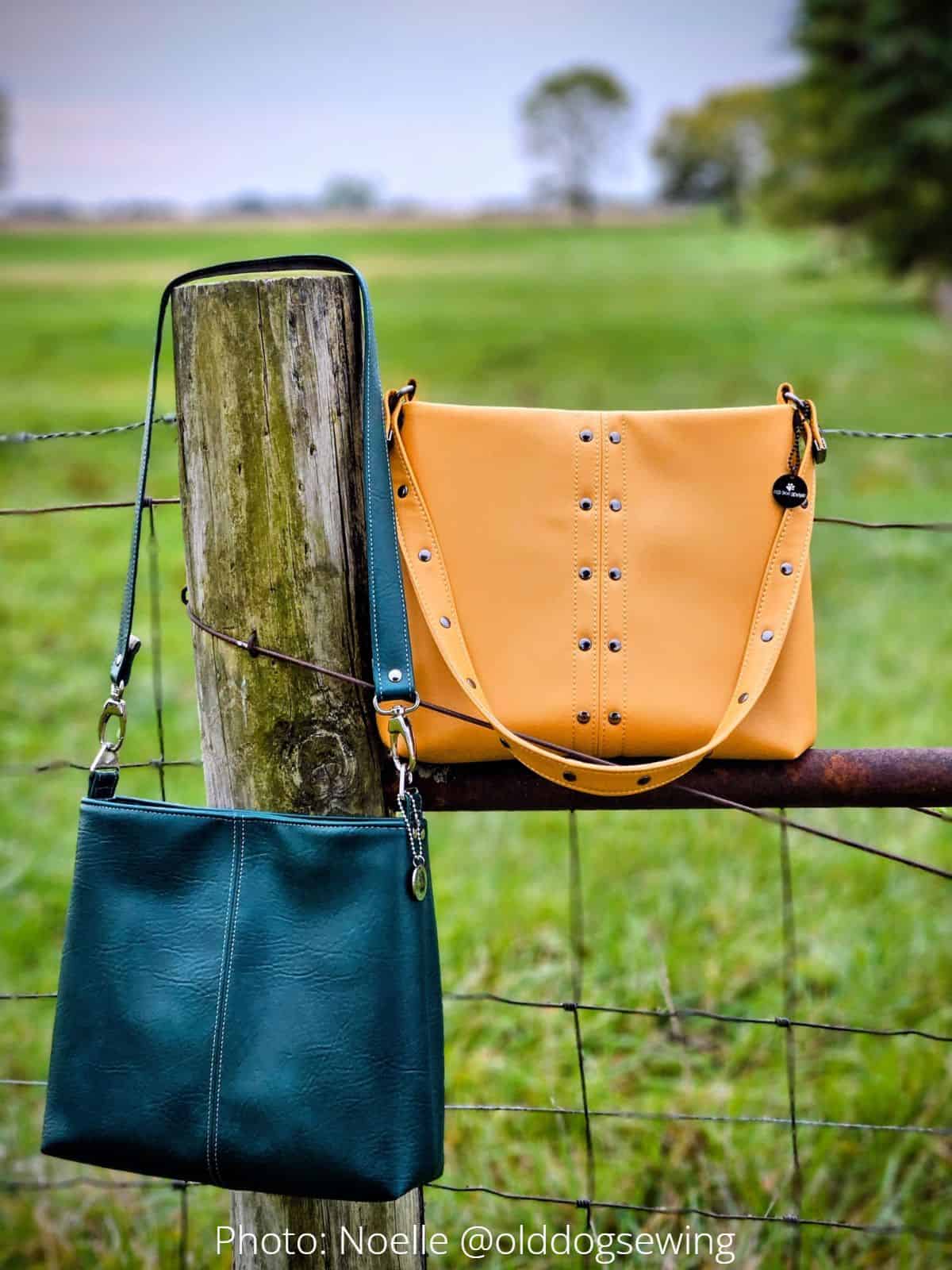 Mustard and teal faux leather Lumera bags with rivet accents and contrast stitching on a farm fence.