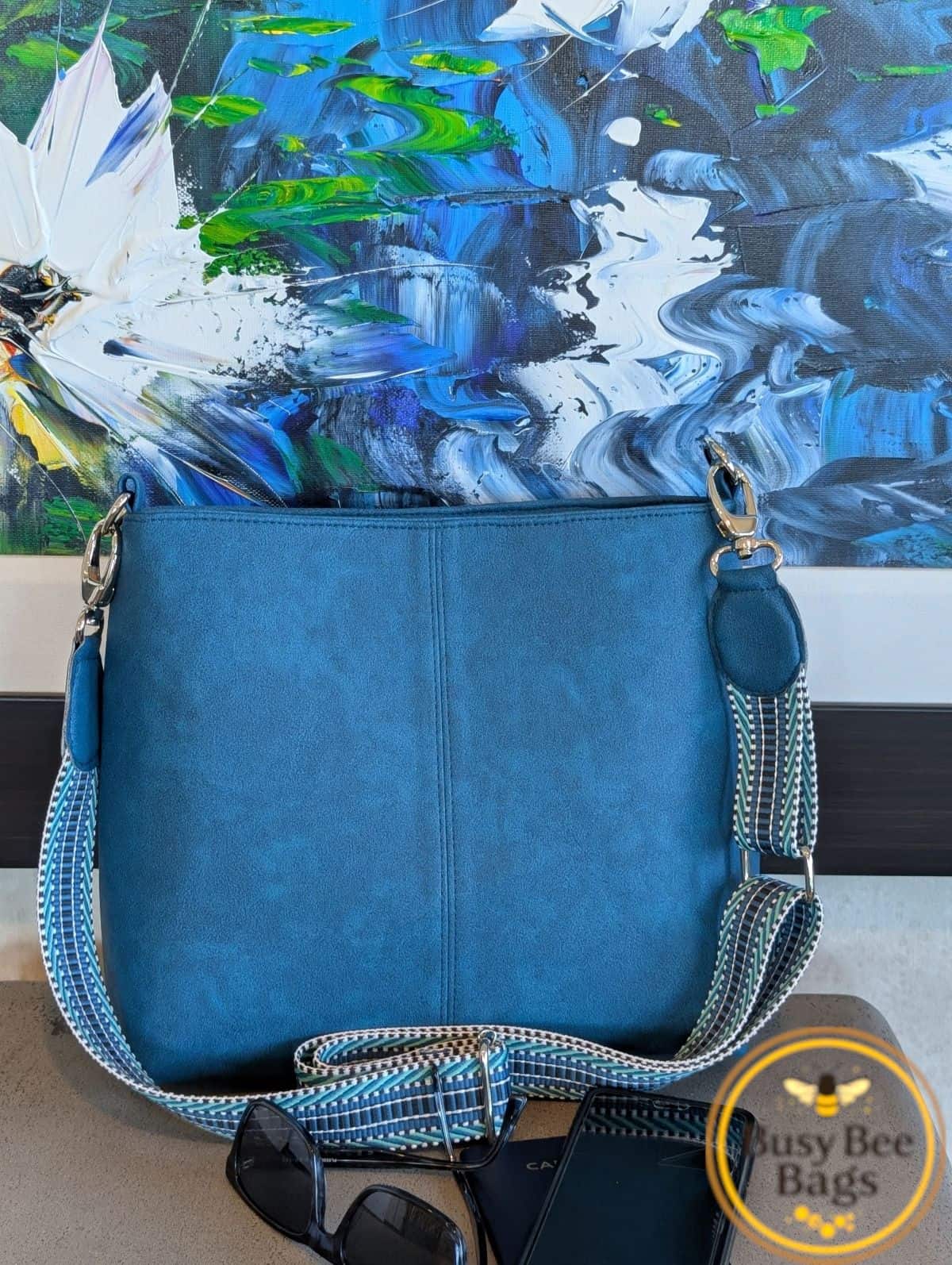 Suede-look blue Lumera bag with patterned webbing strap and silver hardware.