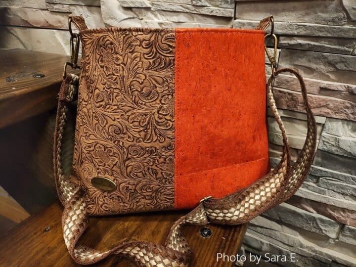 A finished lumera shoulder bag in brown embossed faux leather and orange cork, and a wide webbing strap.