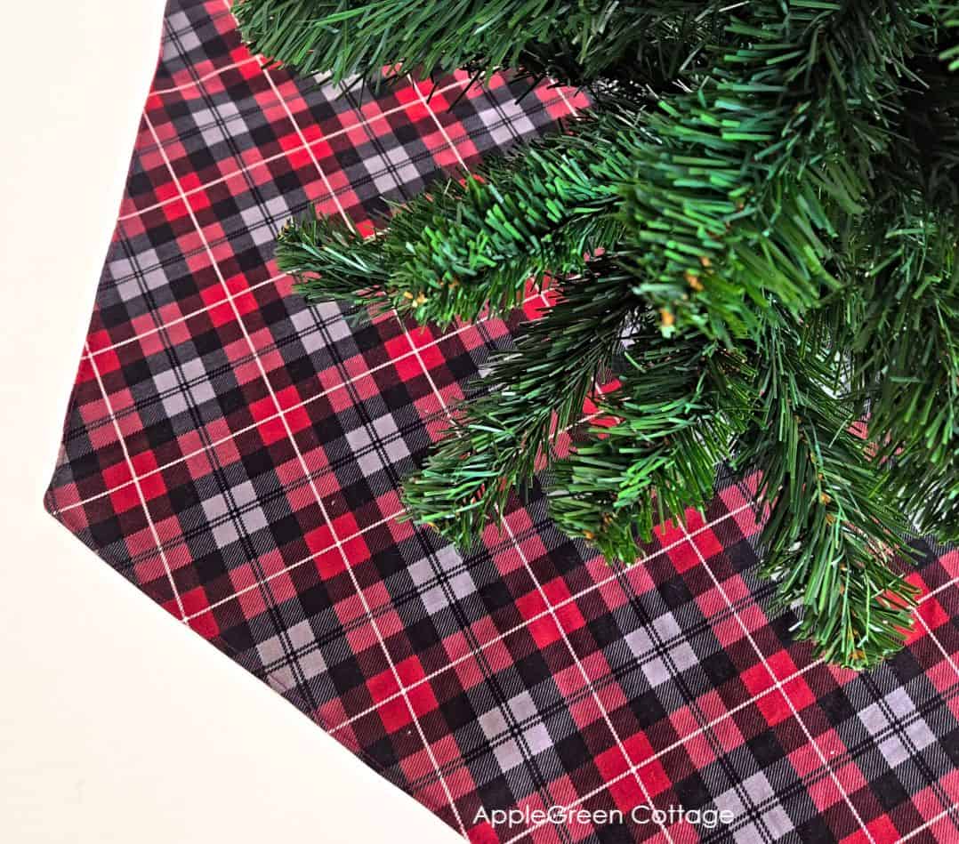 Reversible quilted Christmas tree skirt with plaid fabrics shown and placed under a Christmas tree.