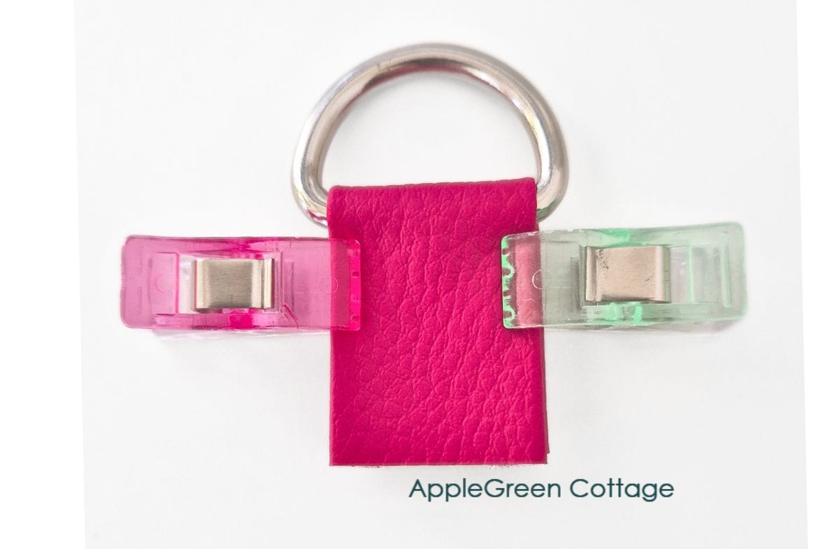 Faux leather strap connector clipped around a D-ring, ready for stitching.