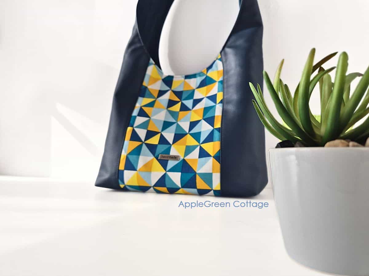 Finished ISKA hobo bag in navy and yellow with geometric center panel, displayed for bagmaking inspiration.