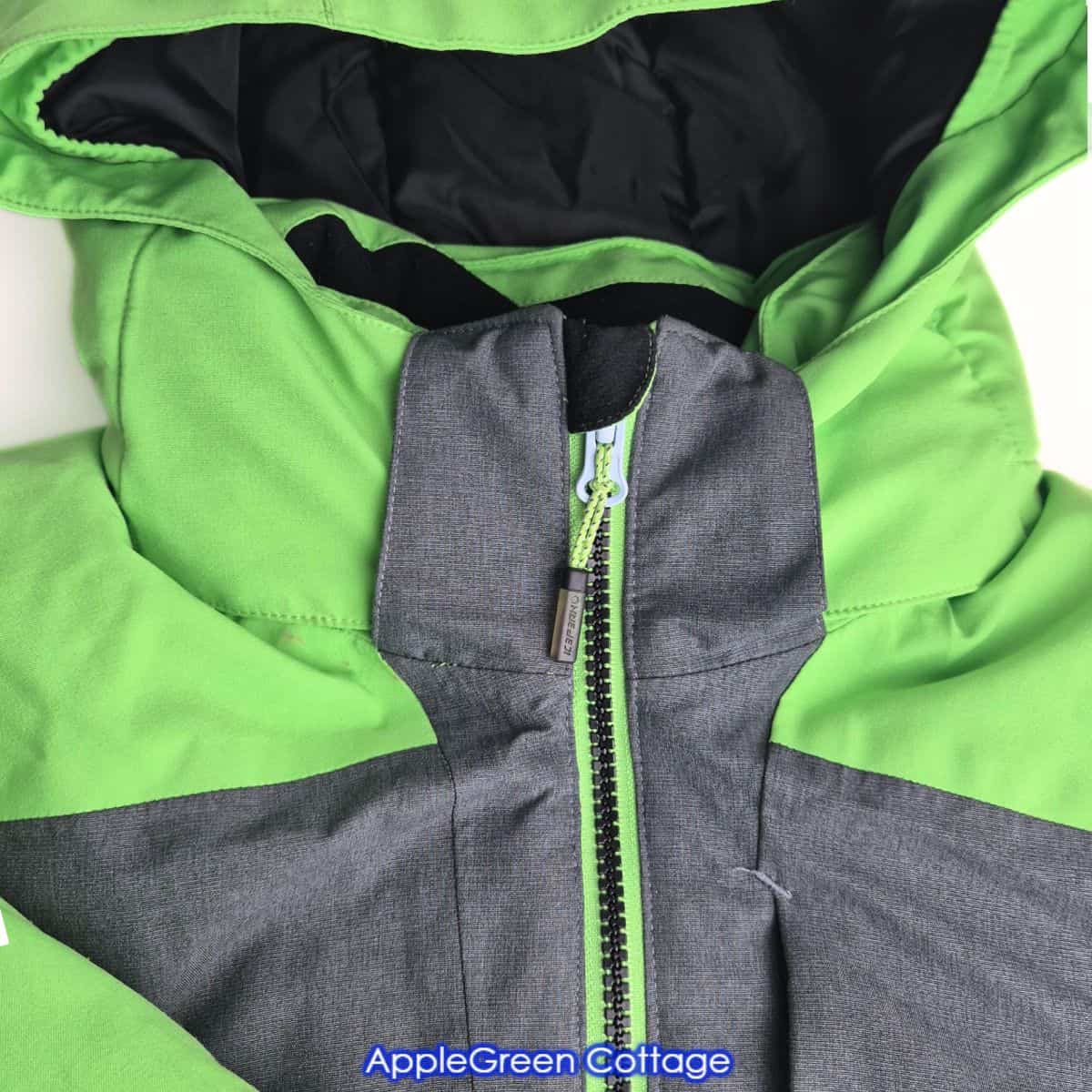 Green jacket zipper with corded zipper pull shown before slider replacement.