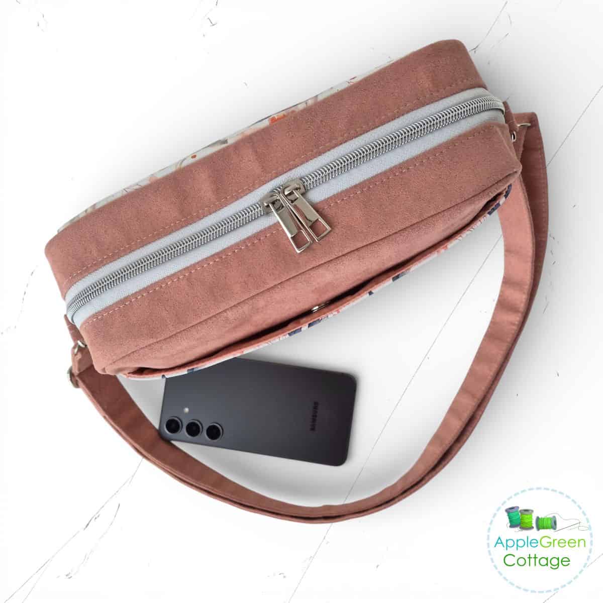 Top view of boxy crossbody bag showing double-pull zipper and structured gusset.