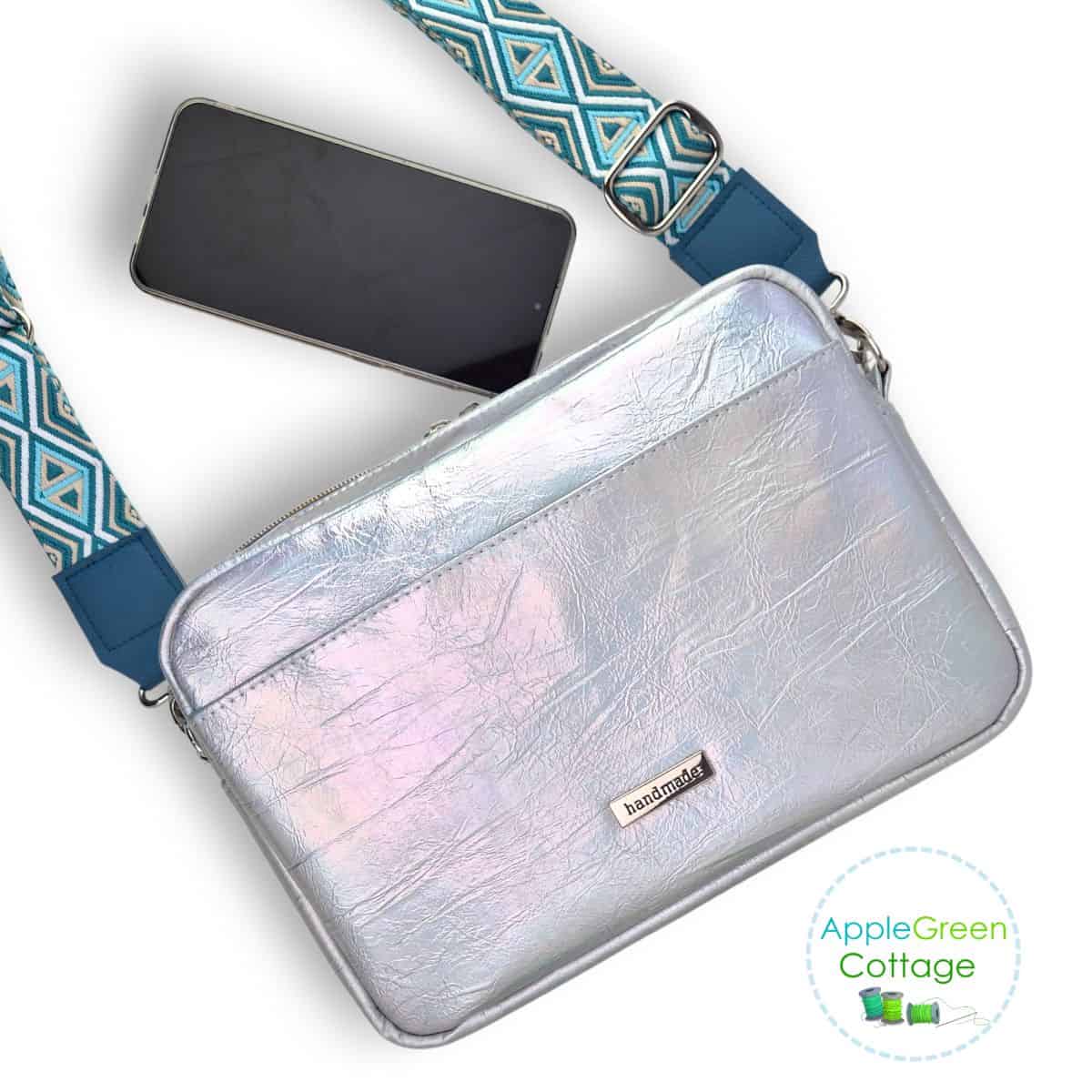 Metallic faux leather boxy crossbody bag with adjustable strap and slim structured profile.