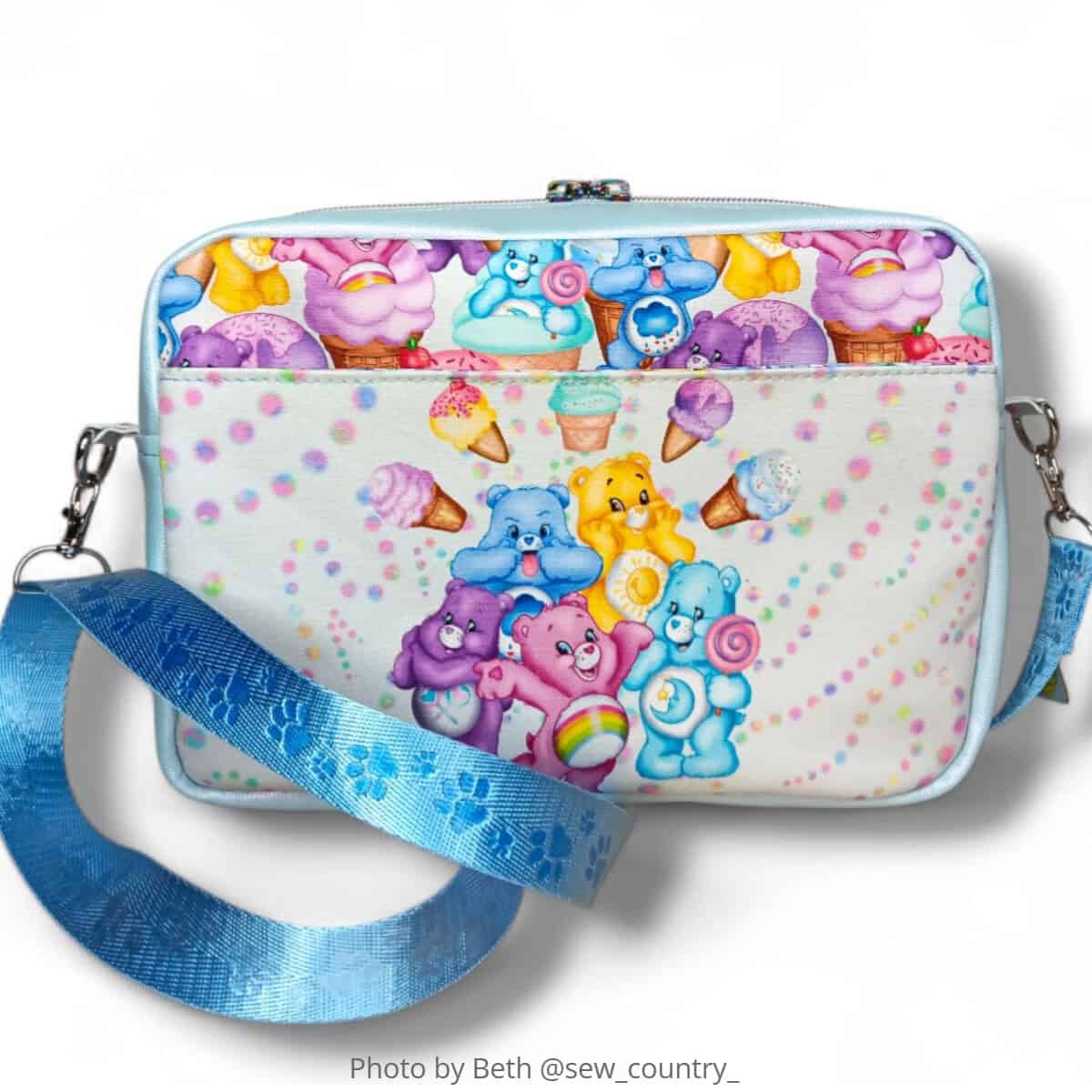 Finished crossbody bag with zip top, front slip pocket, and adjustable webbing strap in printed fabric.